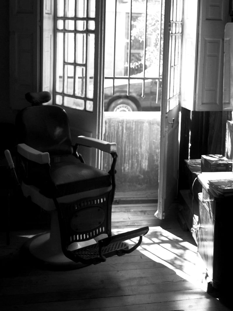A single chair beside the open front door with the street light coming in.